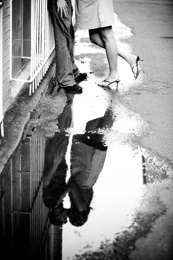 black and white photo - fun perspective of the happily engaged couple kissing in the reflection of a puddle - photo by North Carolina based wedding photographers Cunningham Photo Artists